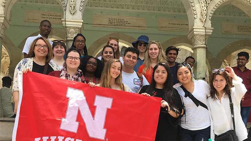 Students hold up a Nebraska flag in front of ornate colonnades in Jaipur, India