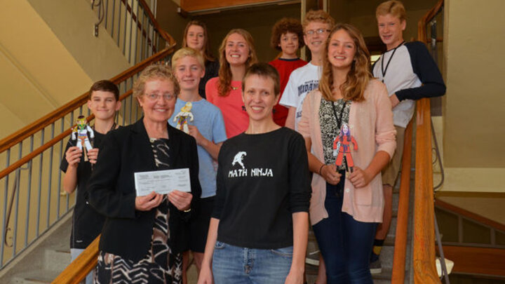 Jocelyn Bosley presents a check for $2,500 to principal, Susette Taylor, and students.