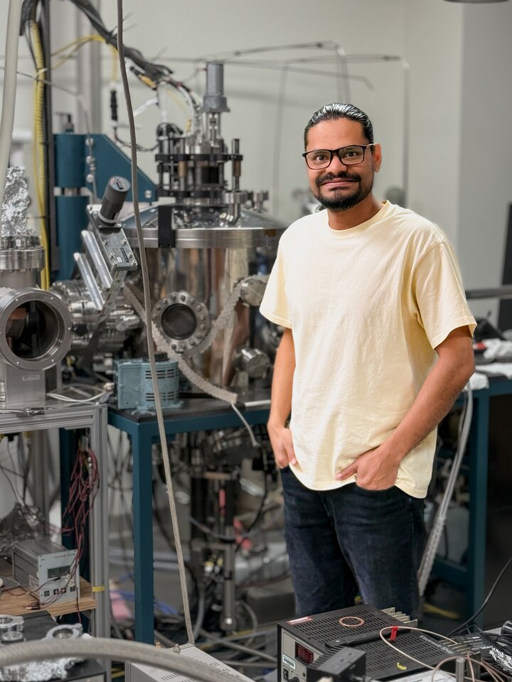 Picture of Rabindra Oliya standing next to physics equipment